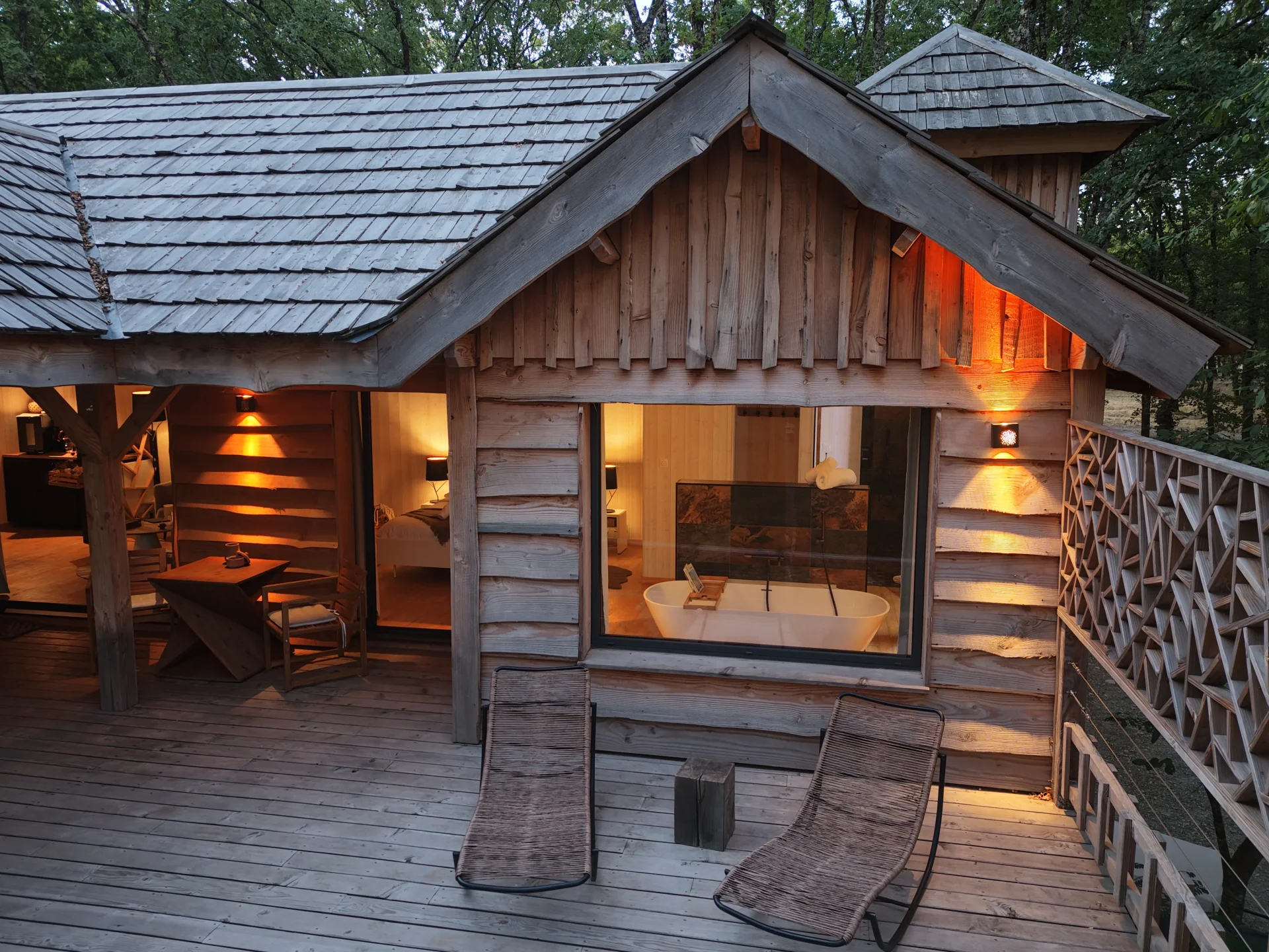 Cabane en bois éclairée avec terrasse au cœur des arbres