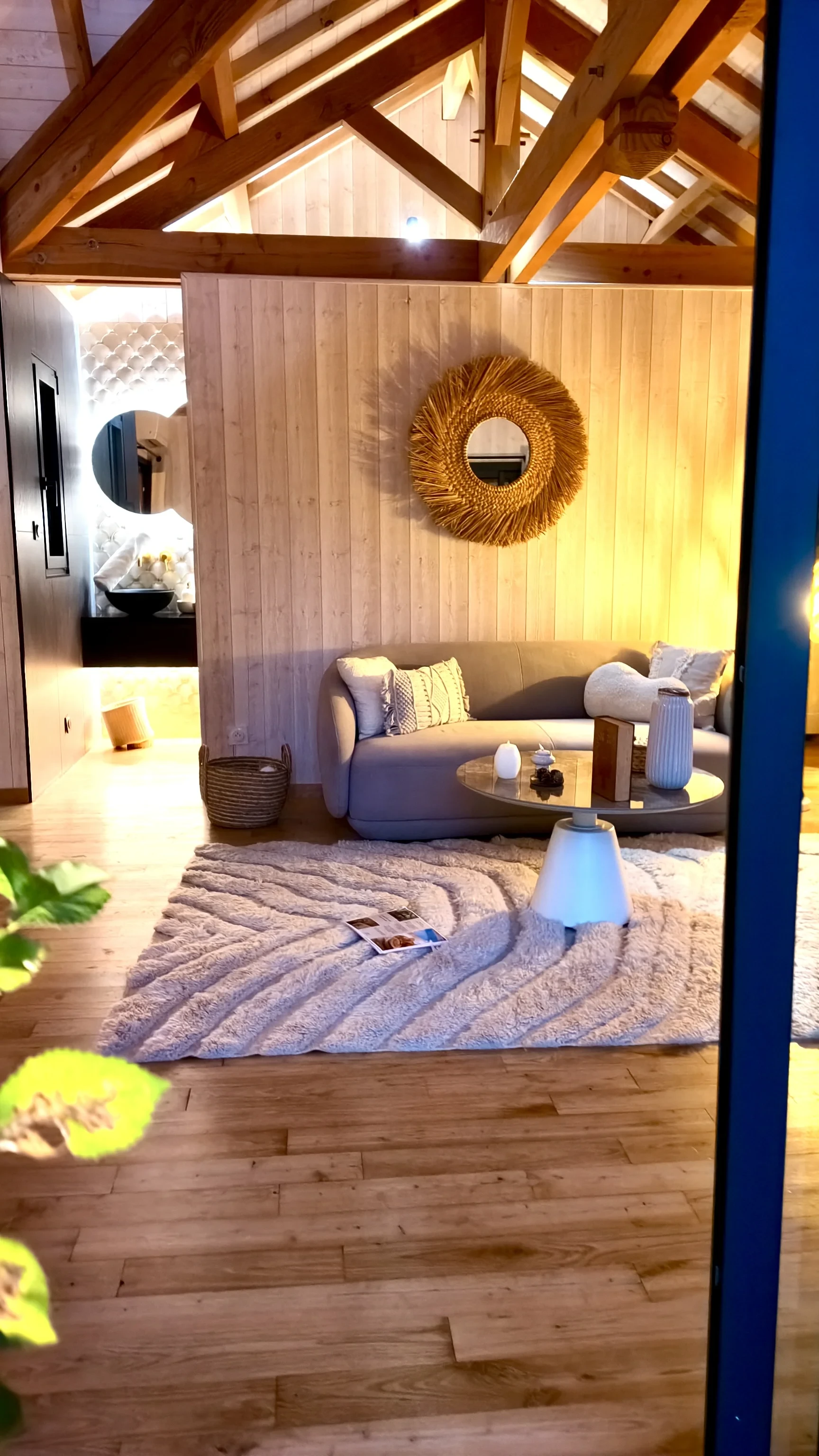 Salon chaleureux sous charpente apparente avec canapé beige