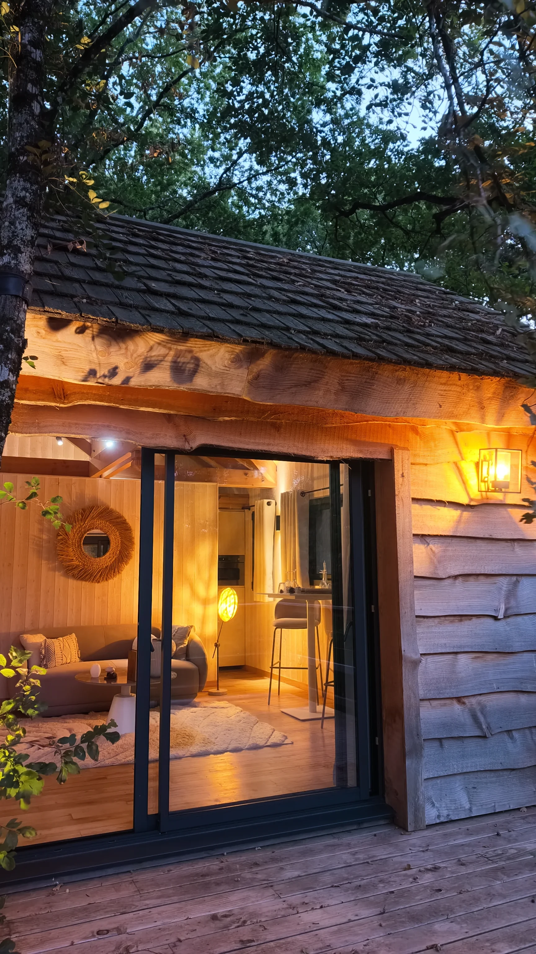 Chalet en bois illuminé sous les arbres au crépuscule