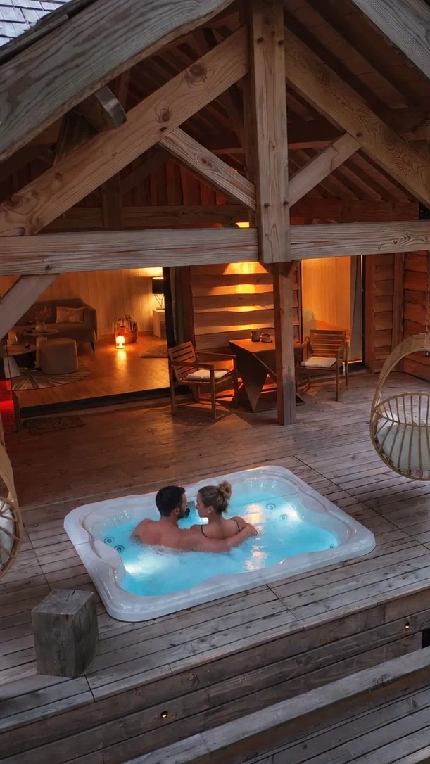 Couple dans un jacuzzi sur terrasse de chalet