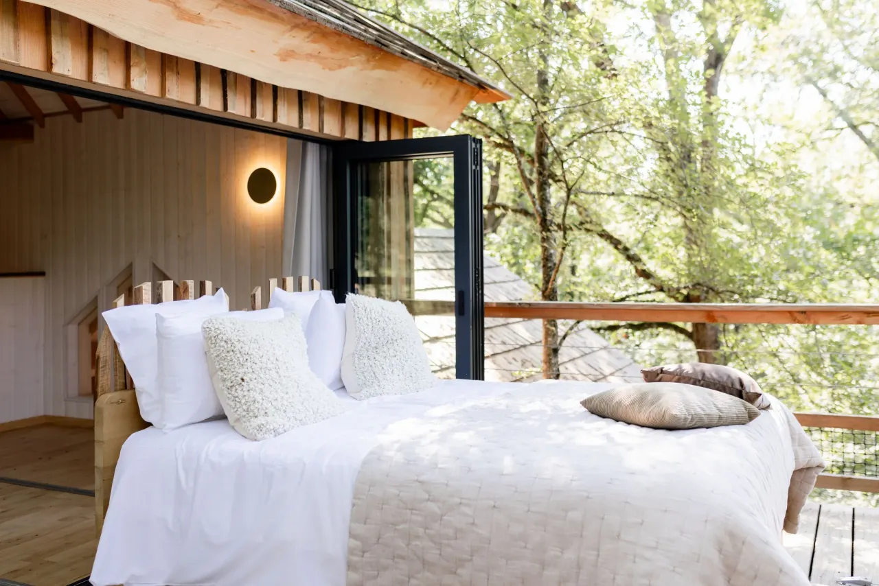 Chambre lumineuse avec lit et balcon en forêt