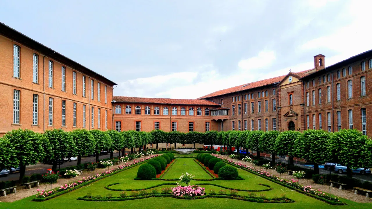 Jardin devant un grand bâtiment historique marron.