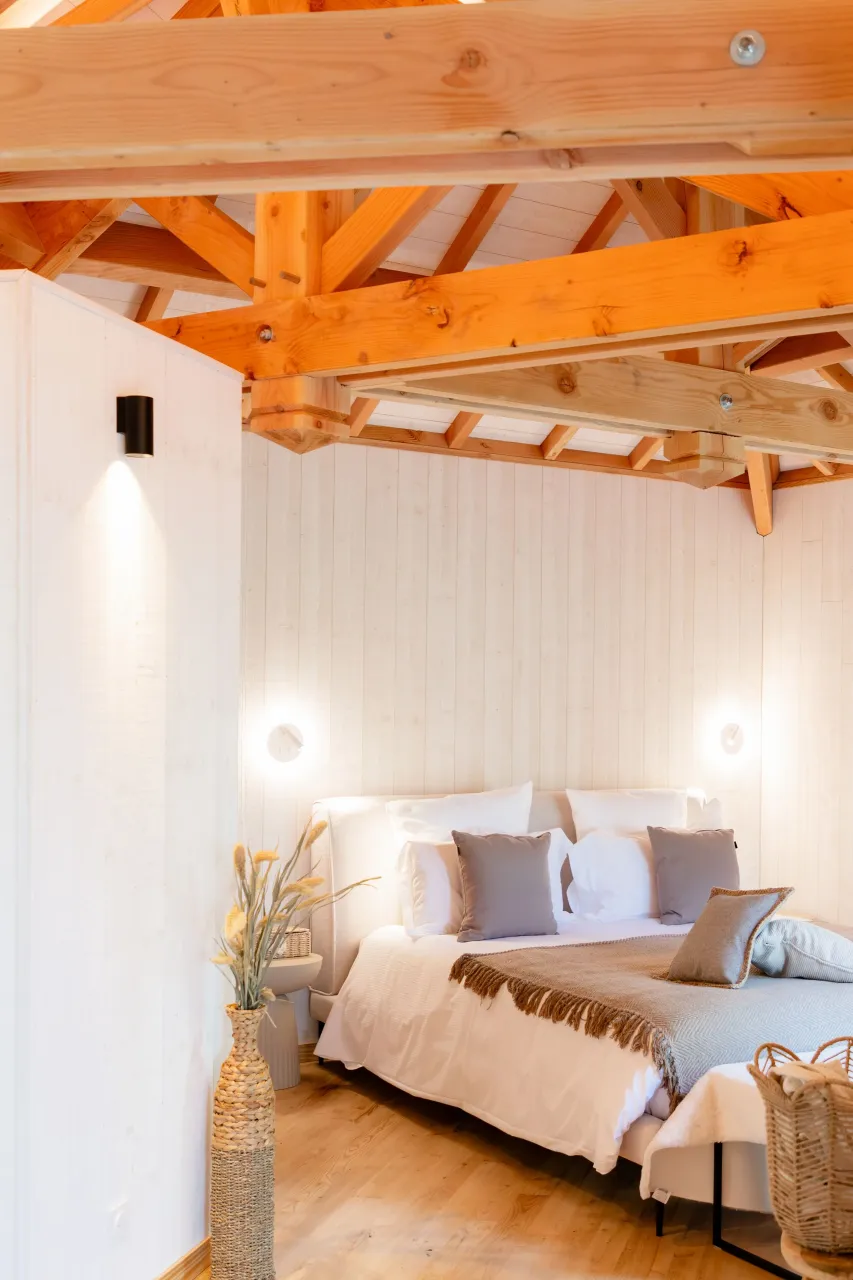 Chambre lumineuse avec poutres apparentes en bois.