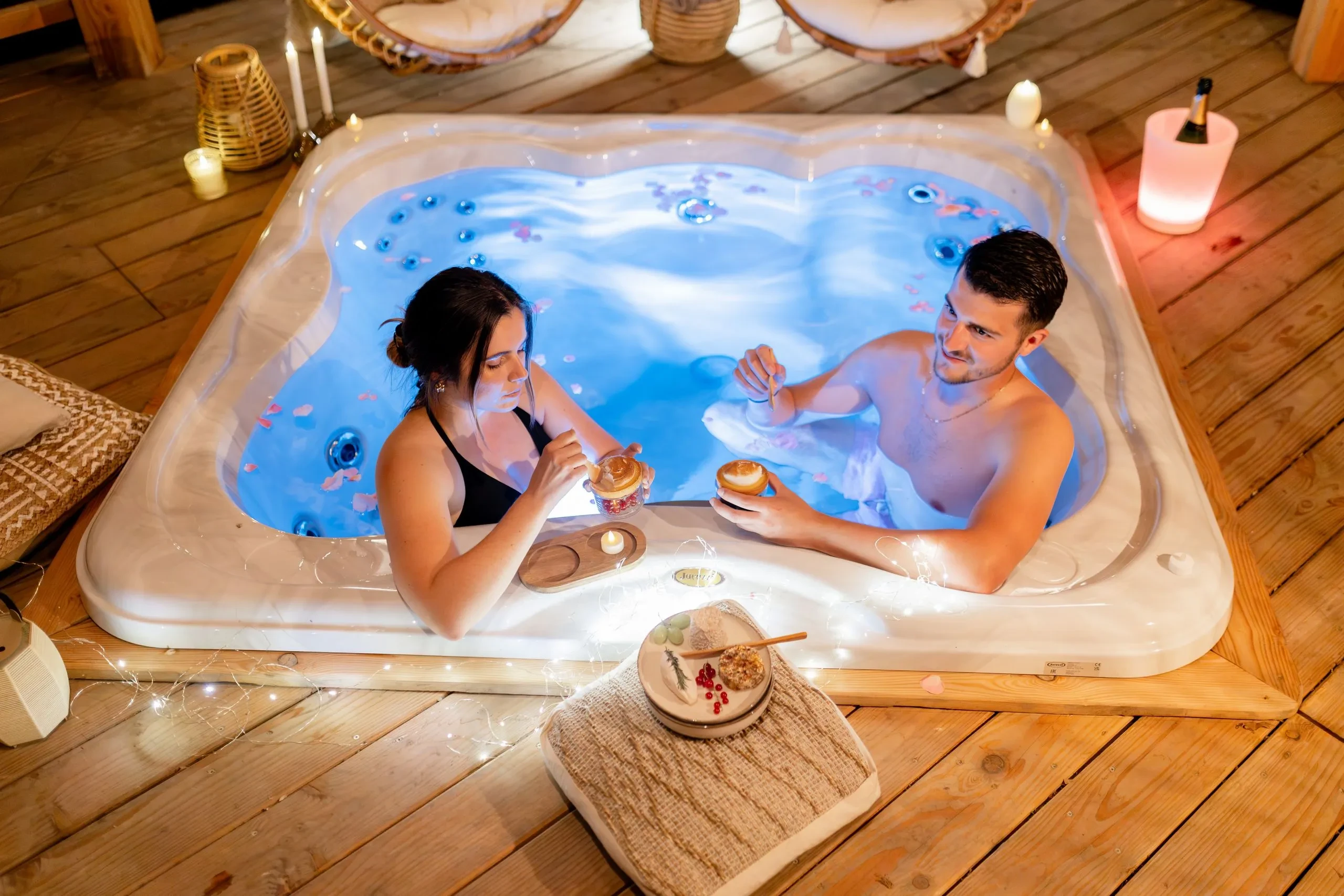 Couple relaxant dans un jacuzzi avec des desserts.